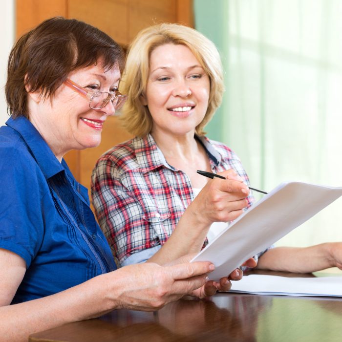 Two smiling elderly woman working at home with contracts
